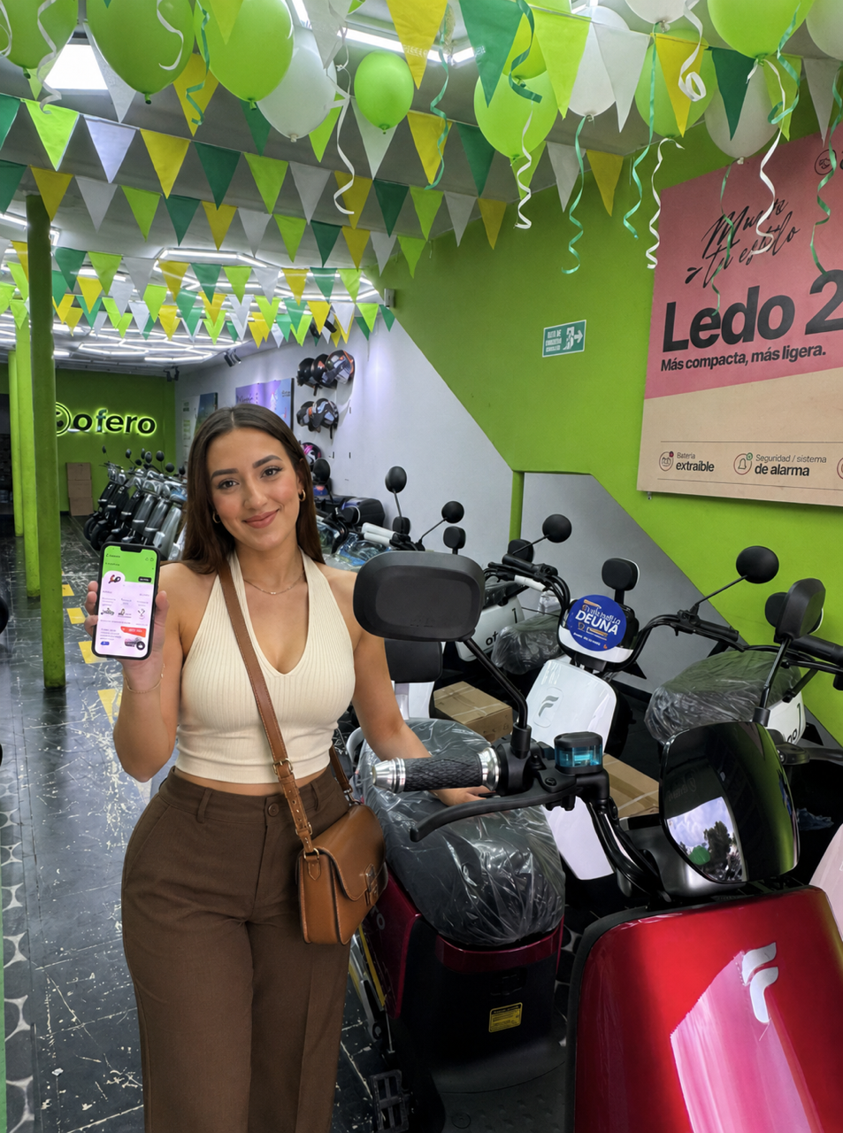 Usuaria de Ofero mostrando la app junto a motos eléctricas